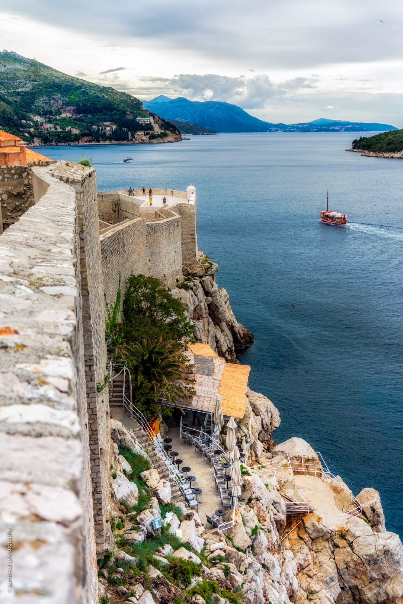 Boats cruising in the Adriatic Sea alongside the City Walls of Dubrovnik